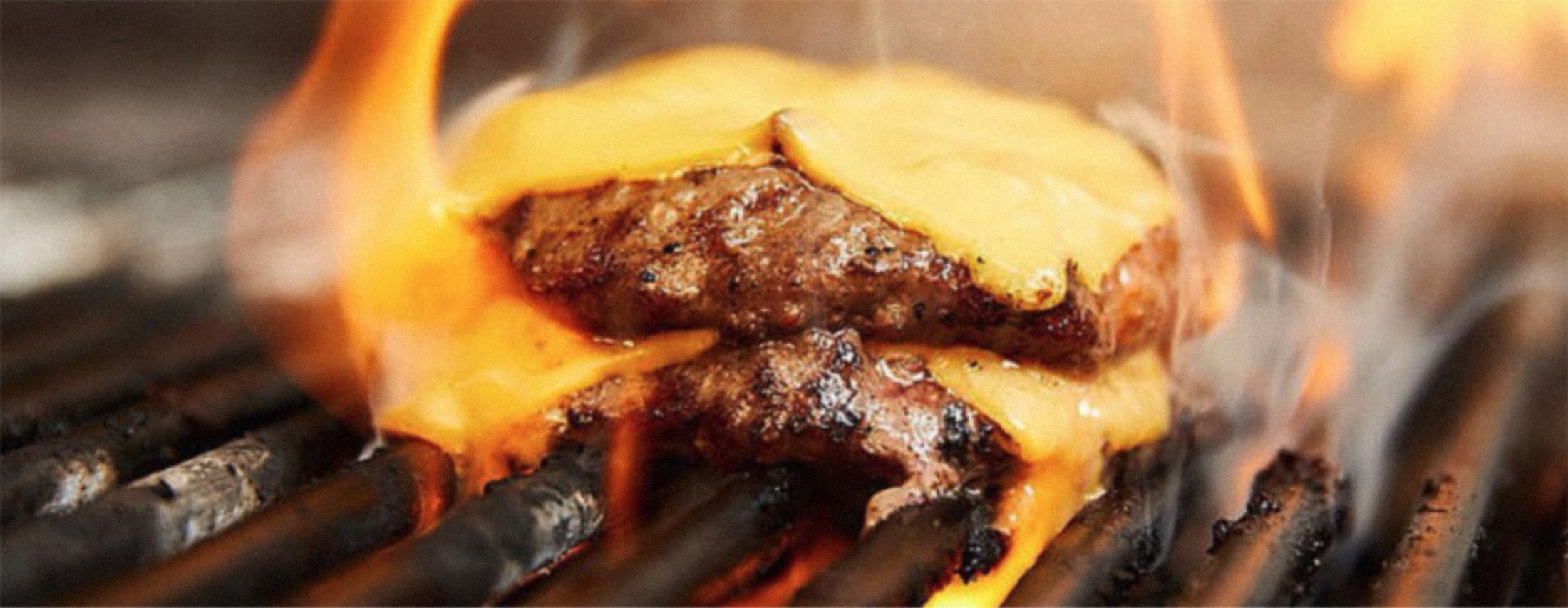 burgers being grilled amongst flames.
